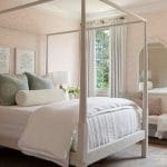 White four-poster bed with sheer curtains and patterned wallpaper.
