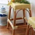 Yellow wicker stool with rattan frame and blue porcelain jar.