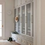 Light gray cabinets with mesh-paneled doors and brass hardware.