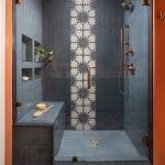 Blue tile shower with glass enclosure and fixtures.