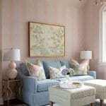 Pink and gold patterned wallpaper, blue sofa, and artwork.