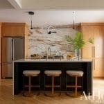 Modern kitchen with marble backsplash, wooden cabinetry, and island seating.