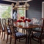 Dining room with plaid wallpaper, dark wood table, and chandelier.