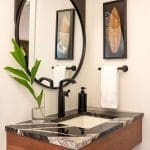 Black vessel sink with marble countertop and wood vanity.
