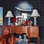 Dark green and red plaid wall with a mirrored octagonal wall decor and lamps.