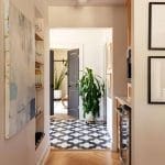Hallway with black and white tile floor, artwork, and shelving.