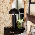 Dark lamps and flowers on a patterned nightstand.