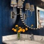 Dark blue wallpaper with marble sink and faucet.