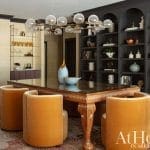 Dark gray wall with arched opening, orange seating, and a large light fixture.