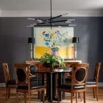 Dark gray wall with a large floral painting and a modern chandelier.