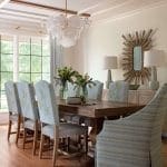 Dining room with a wooden table, upholstered chairs, and a large chandelier.