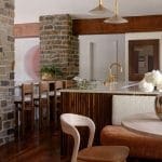 Stone fireplace, wooden kitchen island, and gold pendant lighting.