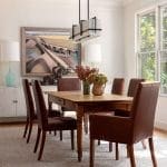 Dining room with wooden table, leather chairs, and artwork.