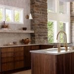 Kitchen with stone pillar, marble countertop, and wooden cabinetry.