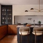 Dark kitchen island with walnut countertop, gold fixtures, and patterned tile.