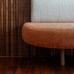 Wooden wall paneling and velvet sofa in a living room.