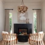 Neutral living room with rattan chairs, textured rug, and a large shell chandelier.