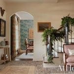Grand entryway with arched doorway, green foliage, and patterned wallpaper.
