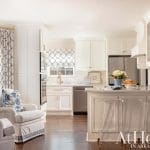 White kitchen with island, blue curtains, and gold accents.
