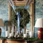 Dark blue wallpaper with a flocked pattern, mirror, and evergreen wreath.