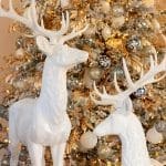 Two white deer statues adorn a heavily decorated Christmas tree.