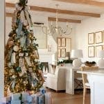 Decorated Christmas tree in a living room with a fireplace and neutral furniture.