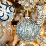 Blue and silver glass ornament on a flocked Christmas tree.