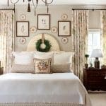 Bedroom with ornate chandelier, framed botanical prints, and patterned drapes.