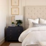 Cream upholstered bed with patterned headboard and framed artwork.