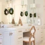 White vanity with marble countertop, silver fixtures, and two sconces.