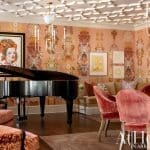 Pink and patterned walls with a grand piano and artwork.