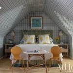 Gabled bedroom with blue and green plaid wallpaper, bed, and furniture.