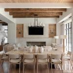 Large dining table with wooden chairs, exposed beam ceiling, and television.