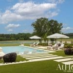 Pool area with lounge chairs, umbrellas, and a lake in Arkansas.