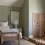 Green bedroom with a wooden bed, dresser, and wardrobe.