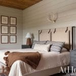 Bedroom with wood-paneled walls, antler headboard, and framed artwork.