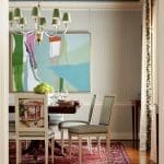 Dining room with blue patterned ceiling, artwork, and upholstered chairs.