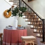 White table with red fabric, books, and a wooden stool near a staircase.