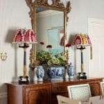 Dark wood cabinet with ornate mirror, lamps, and blue and white porcelain.