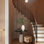 Wooden panel staircase with a small table and ottoman.