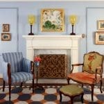 Blue wall, marble fireplace, and patterned rug.