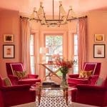 Pink room with patterned floor, red chairs, and a chandelier.