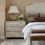 Cream-colored headboard, nightstand, and pillows in a bedroom.