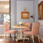 Light blue walls, patterned chairs, and a small table with a floral arrangement.