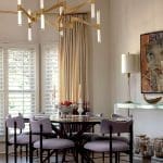 Dining room with a purple table, gold chandelier, and beige curtains.