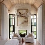 Wooden beamed ceiling, stone fireplace, and two chairs in a spacious room.