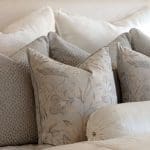 Layered linen pillows with floral pattern on a bed.