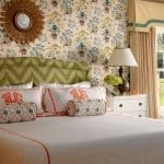 Bedroom with patterned wallpaper, headboard, pillows, and dresser.