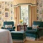 Turquoise armchairs with patterned wallpaper and window view.
