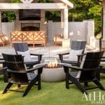 Outdoor living room with fire pit, black Adirondack chairs, and covered seating area